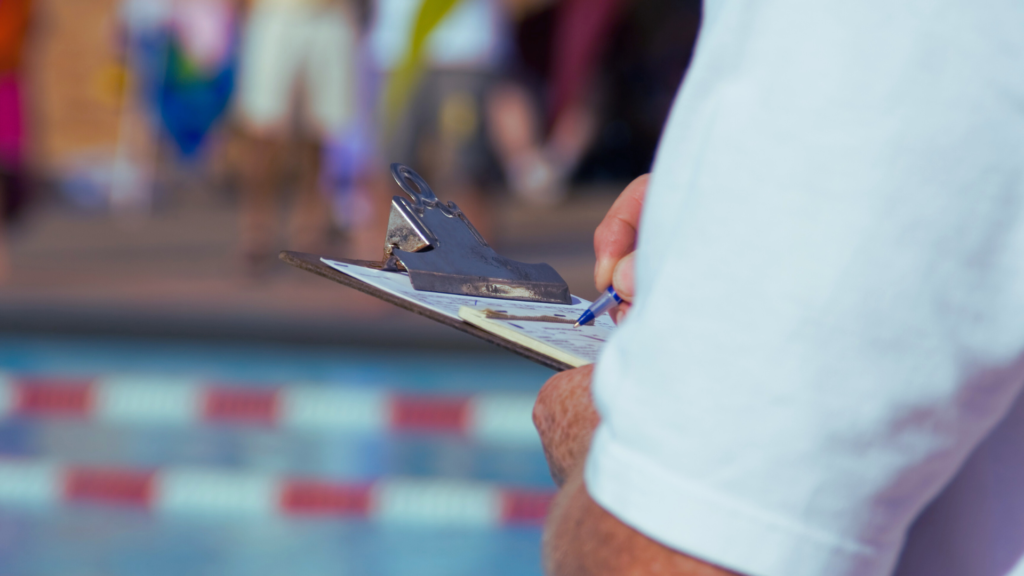A man holding a clipboard at a swim meet.