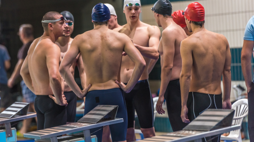 A group of swimmers wearing tech suits standing in a pool.