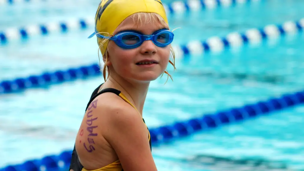 A young swimmer donning a swim cap and goggles for a competition.
